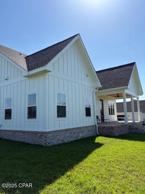 3391 Grey Oak Way, Marianna, FL 32446 - view of side of home with a yard, a patio, board and batten siding, and a shingled roof