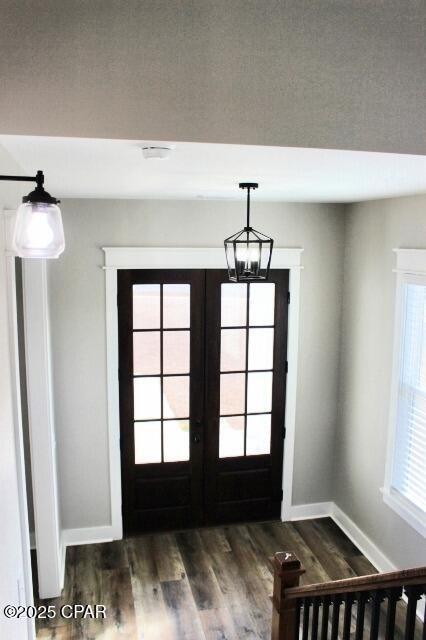 foyer featuring french doors, dark hardwood / wood-style flooring, a chandelier, and a wealth of natural light