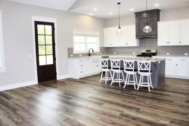 kitchen with decorative light fixtures, white cabinets, a center island, a kitchen breakfast bar, and stainless steel electric range oven