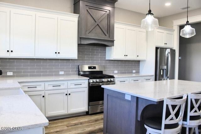 kitchen featuring tasteful backsplash, appliances with stainless steel finishes, hanging light fixtures, and white cabinetry