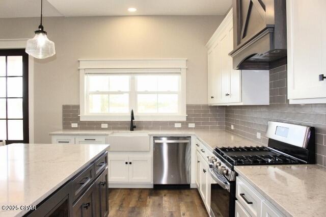 kitchen with stainless steel appliances, white cabinets, decorative light fixtures, and premium range hood