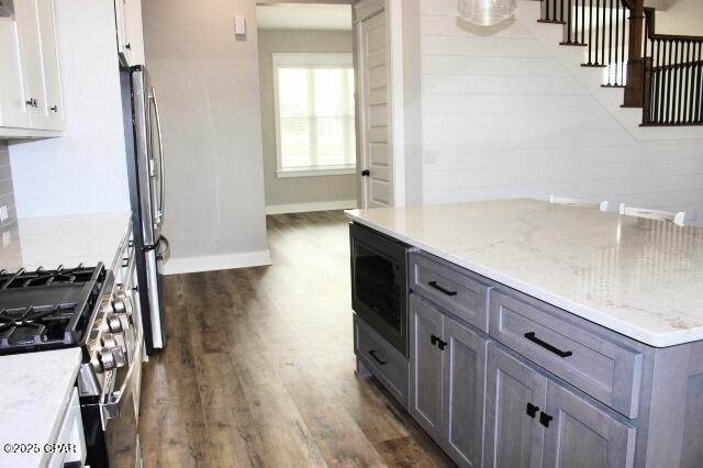 kitchen featuring gray cabinets, appliances with stainless steel finishes, light stone countertops, dark hardwood / wood-style floors, and white cabinets