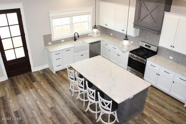 kitchen featuring light stone countertops, backsplash, white cabinets, appliances with stainless steel finishes, and sink