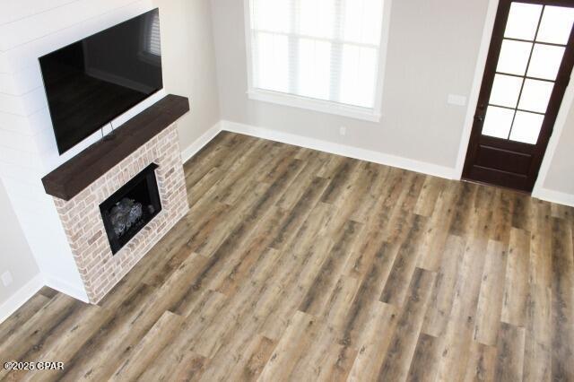 unfurnished living room with a brick fireplace and hardwood / wood-style flooring