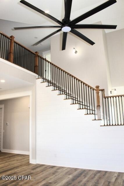 stairs featuring ceiling fan and hardwood / wood-style floors