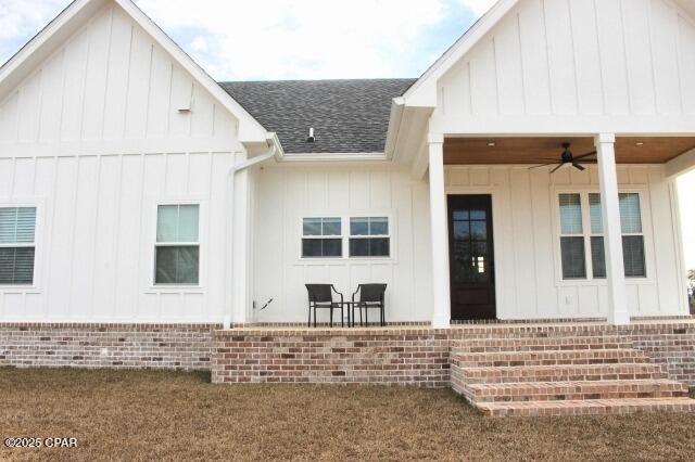 doorway to property with ceiling fan and a yard