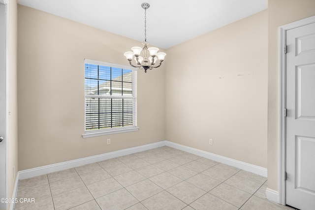 empty room with light tile patterned floors, baseboards, and a chandelier