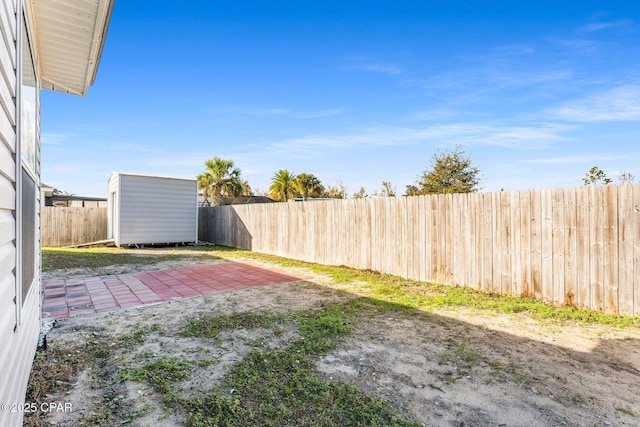 view of yard featuring a patio area, a fenced backyard, a storage shed, and an outdoor structure