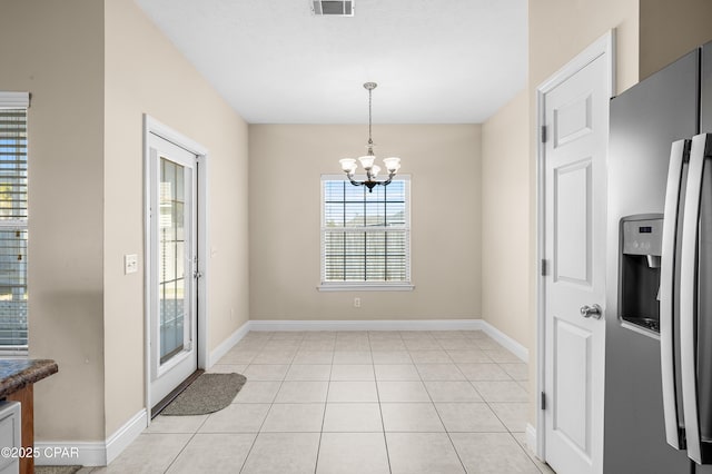 unfurnished dining area with an inviting chandelier, visible vents, light tile patterned floors, and baseboards