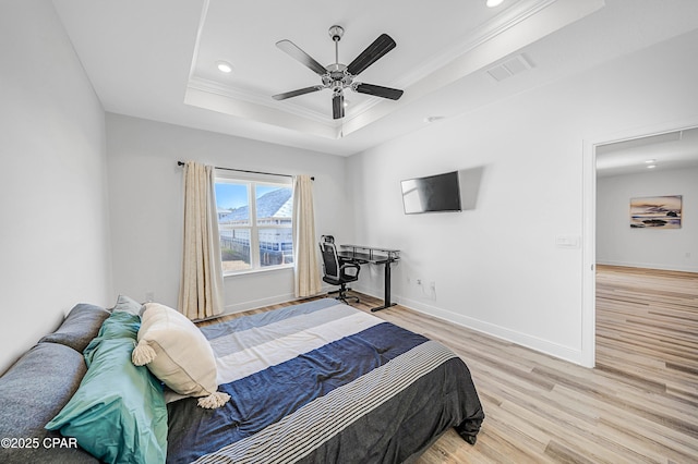 bedroom with crown molding, ceiling fan, a raised ceiling, and light hardwood / wood-style flooring