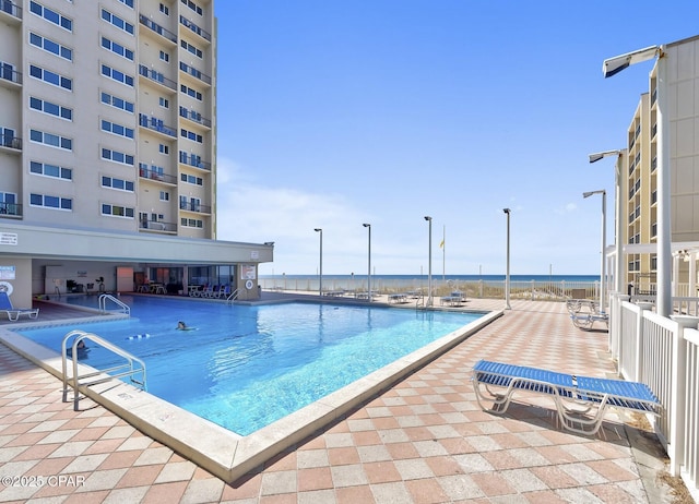 view of pool featuring a water view and a patio