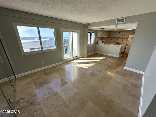 unfurnished living room featuring a textured ceiling and a water view