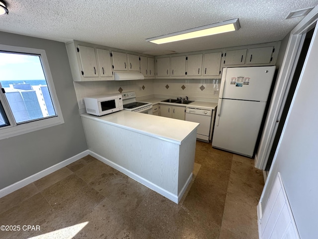 kitchen featuring white appliances, a textured ceiling, decorative backsplash, sink, and kitchen peninsula