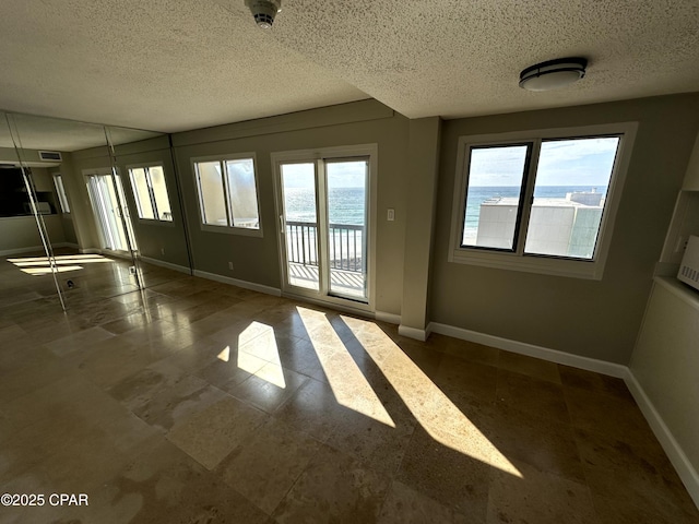 spare room with a water view and a textured ceiling