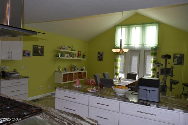 kitchen featuring vaulted ceiling, stone counters, pendant lighting, oven, and white cabinets