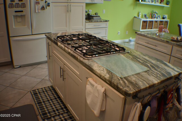 kitchen with white cabinetry, light tile patterned floors, and light stone counters