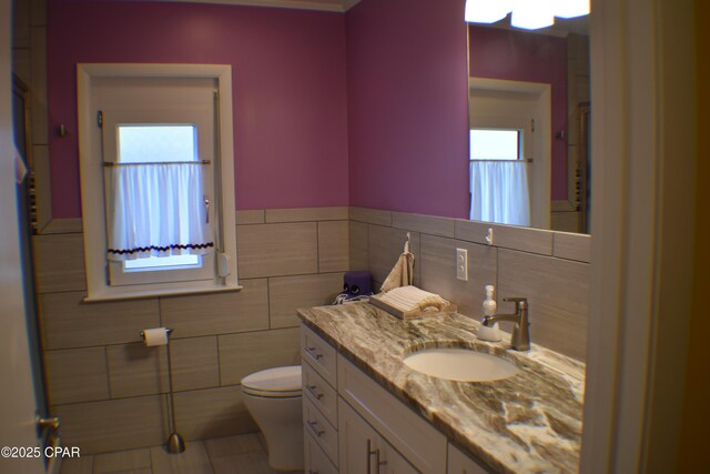 bathroom with tile walls, vanity, toilet, a chandelier, and walk in shower