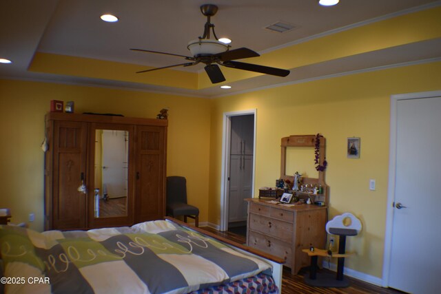 bedroom featuring dark hardwood / wood-style floors, ceiling fan, and a tray ceiling