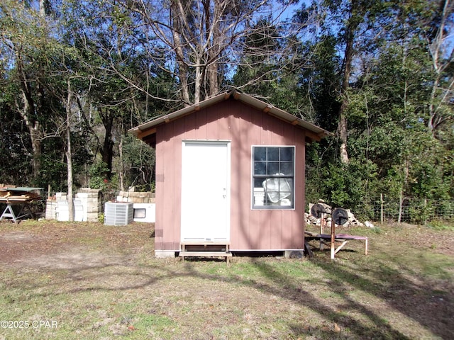 view of outbuilding featuring central AC unit and a lawn