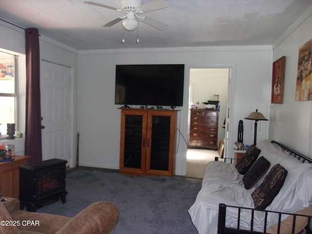 carpeted living room featuring ceiling fan, ornamental molding, and a wood stove