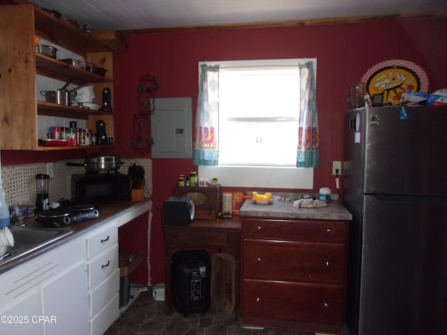 kitchen with electric panel, decorative backsplash, fridge, sink, and white cabinetry