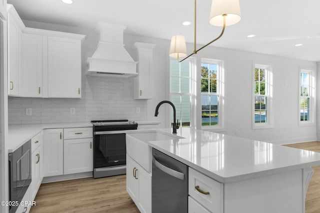 kitchen with premium range hood, white cabinets, a center island with sink, and stainless steel appliances