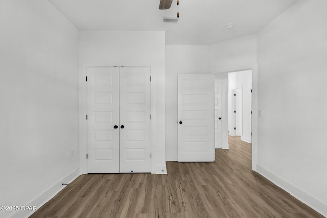 unfurnished bedroom featuring ceiling fan, a closet, and hardwood / wood-style flooring