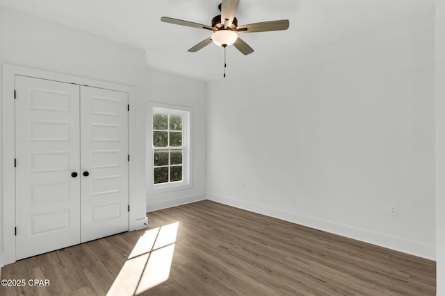 unfurnished bedroom with ceiling fan, a closet, and hardwood / wood-style flooring