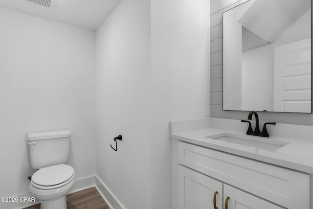 bathroom with toilet, hardwood / wood-style floors, and vanity