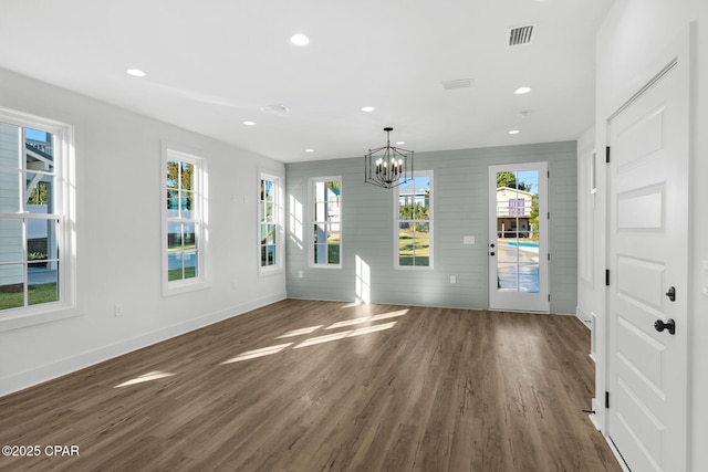 interior space featuring plenty of natural light, an inviting chandelier, dark hardwood / wood-style flooring, and wood walls