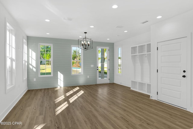 spare room with dark hardwood / wood-style floors, wood walls, and a chandelier