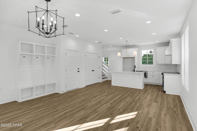 kitchen with backsplash, decorative light fixtures, wood-type flooring, a kitchen island, and white cabinets