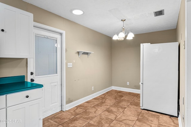 unfurnished dining area featuring a textured ceiling, light tile patterned floors, and a chandelier