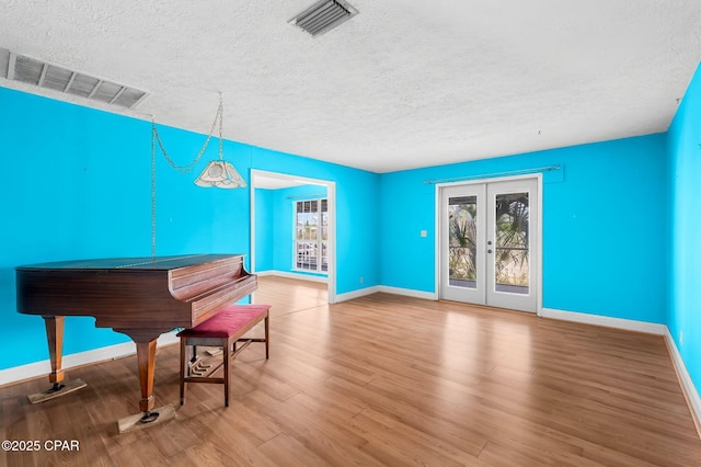 miscellaneous room with hardwood / wood-style flooring, a textured ceiling, and french doors