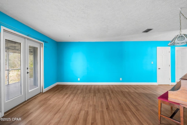 unfurnished living room with hardwood / wood-style flooring, a textured ceiling, and french doors