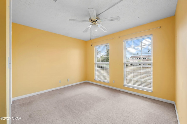 empty room with a textured ceiling, ceiling fan, and light colored carpet