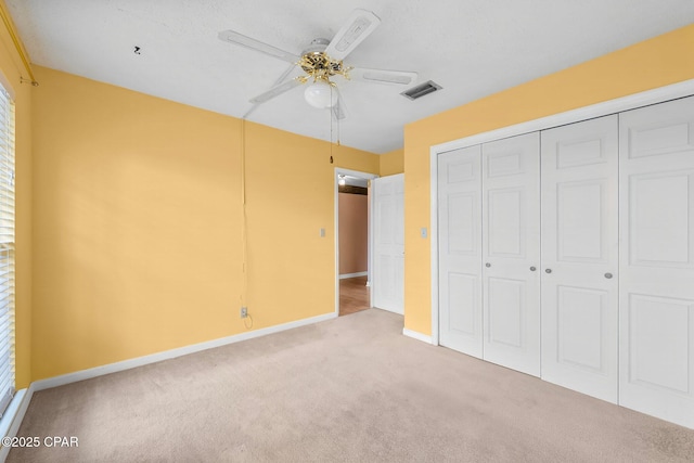 unfurnished bedroom featuring ceiling fan, a closet, and light carpet