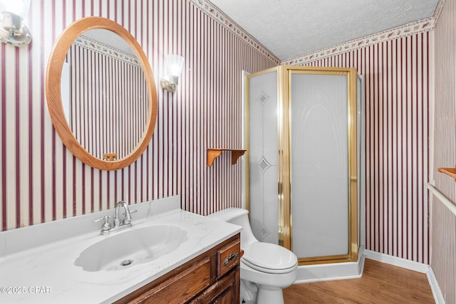 bathroom with a textured ceiling, vanity, hardwood / wood-style flooring, toilet, and a shower with shower door