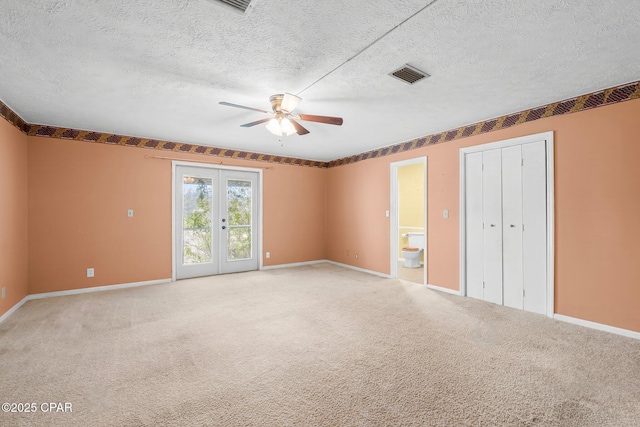 unfurnished bedroom featuring ceiling fan, connected bathroom, carpet, and french doors