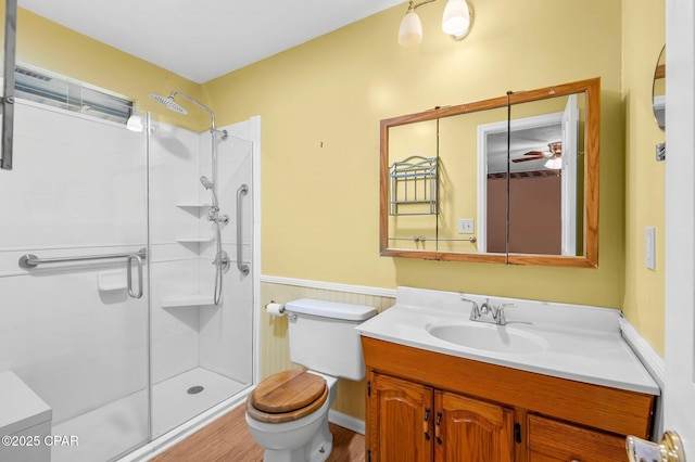 bathroom with toilet, vanity, ceiling fan, wood-type flooring, and an enclosed shower