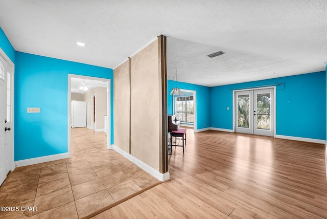 entrance foyer featuring ceiling fan, light hardwood / wood-style floors, a textured ceiling, and french doors