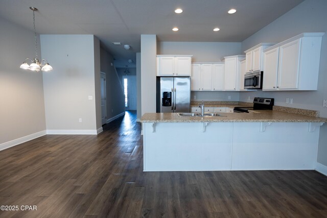 kitchen featuring kitchen peninsula, stainless steel appliances, a kitchen breakfast bar, pendant lighting, and sink