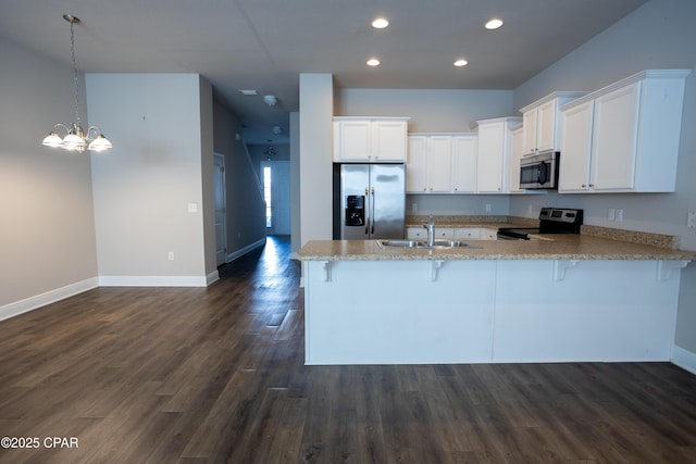 kitchen with appliances with stainless steel finishes, a kitchen bar, sink, and white cabinets