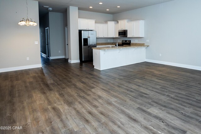 kitchen featuring decorative light fixtures, kitchen peninsula, stainless steel appliances, white cabinets, and ceiling fan with notable chandelier