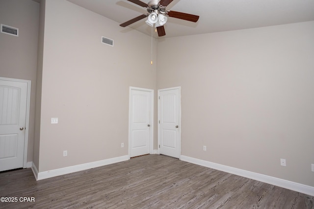 empty room featuring ceiling fan, wood-type flooring, and high vaulted ceiling