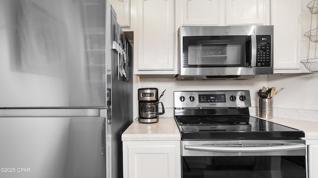 kitchen featuring stainless steel appliances and white cabinetry