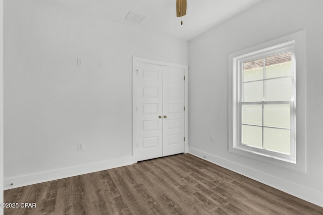 empty room with ceiling fan, plenty of natural light, and wood-type flooring