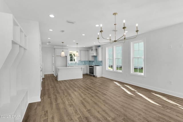 kitchen featuring backsplash, a kitchen island, pendant lighting, electric range, and wall chimney exhaust hood