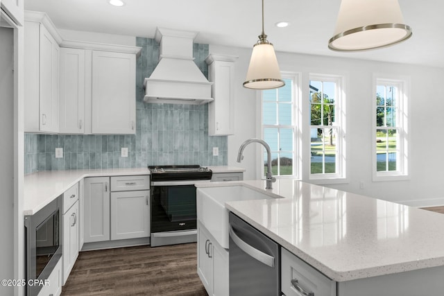 kitchen featuring premium range hood, white cabinetry, stainless steel appliances, tasteful backsplash, and light stone counters