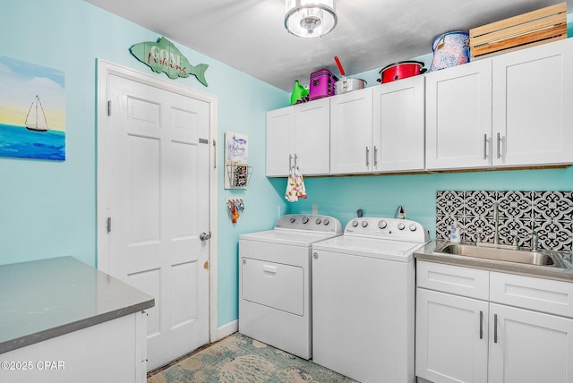 clothes washing area with cabinets, sink, and separate washer and dryer